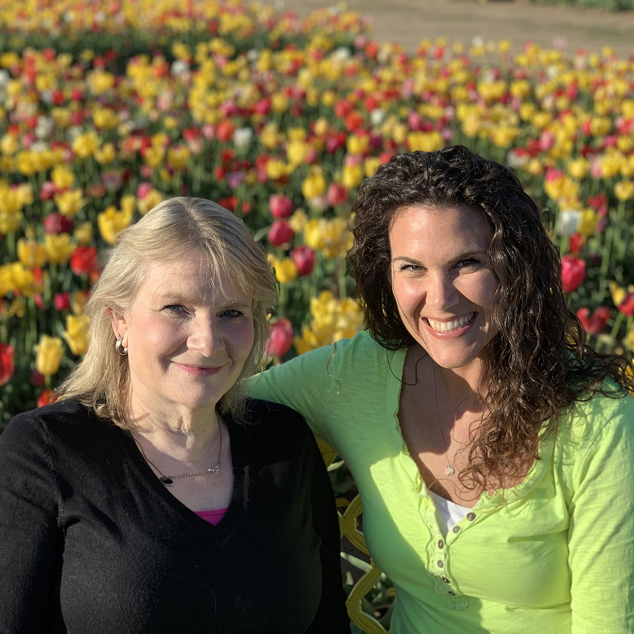 Angie Normie sitting with her aunt Brenda in front of a field of yellow and red tulips.
